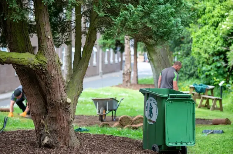 Two Silver Tree Services staff working on landscaping a public green space.