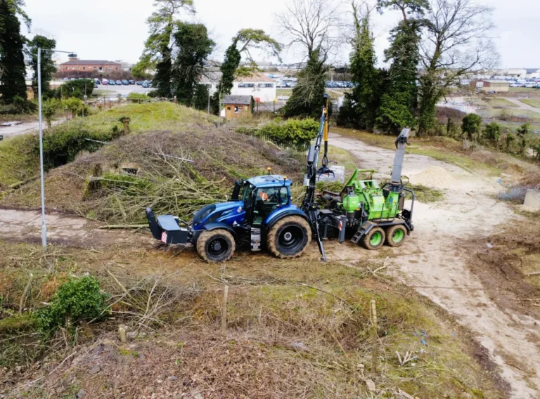 A shot of a valtra tractor and chipper up high from a drone.